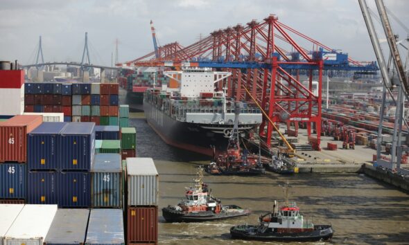 a tug boat in the water next to a large cargo ship