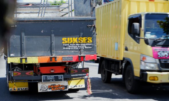 a yellow truck driving down a street next to a yellow truck