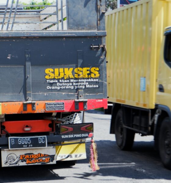 a yellow truck driving down a street next to a yellow truck