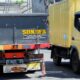 a yellow truck driving down a street next to a yellow truck