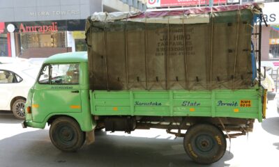 green and brown drop-side truck near gray building