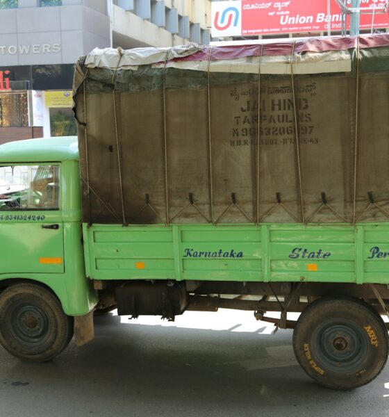 green and brown drop-side truck near gray building