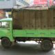 green and brown drop-side truck near gray building